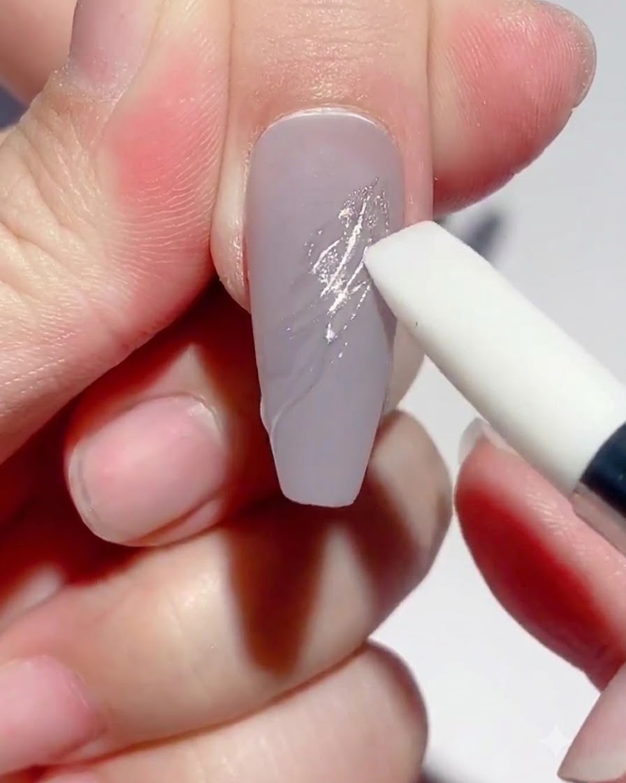 Embout en silicone frottant des pigments chrome argentés sur les reliefs en gel dun ongle.
