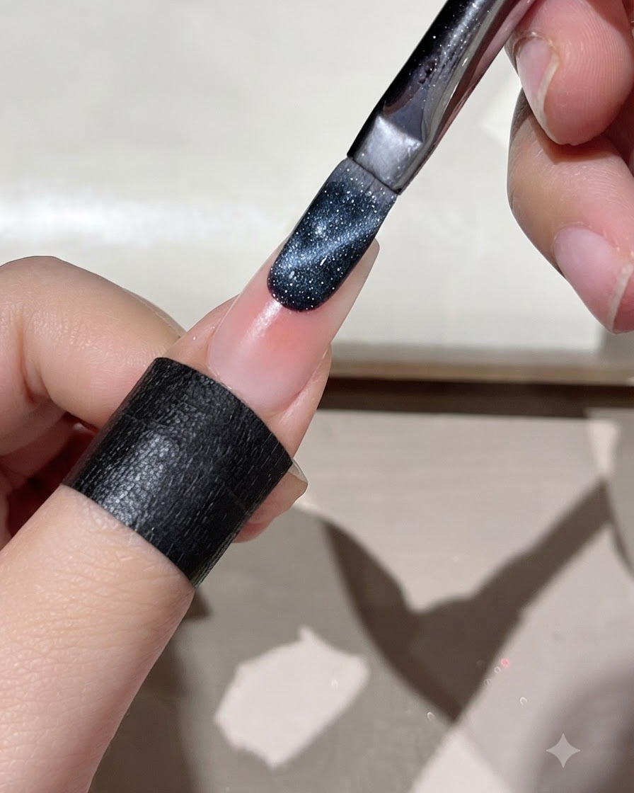 Un pinceau appliquant du gel œil de chat bleu foncé sur le bord dun ongle préparé.