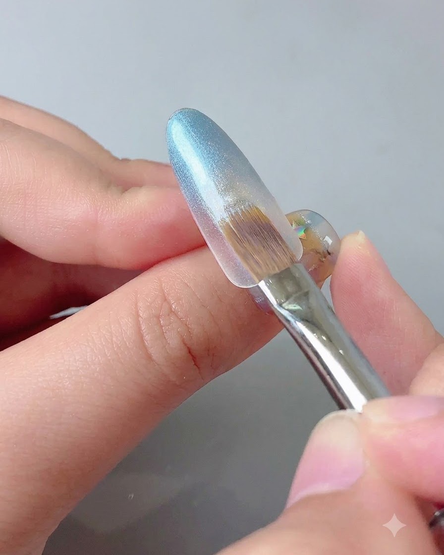 Un outil magnétique tenu près de la pointe dun ongle en gel bleu pour concentrer léclat cat eye.
