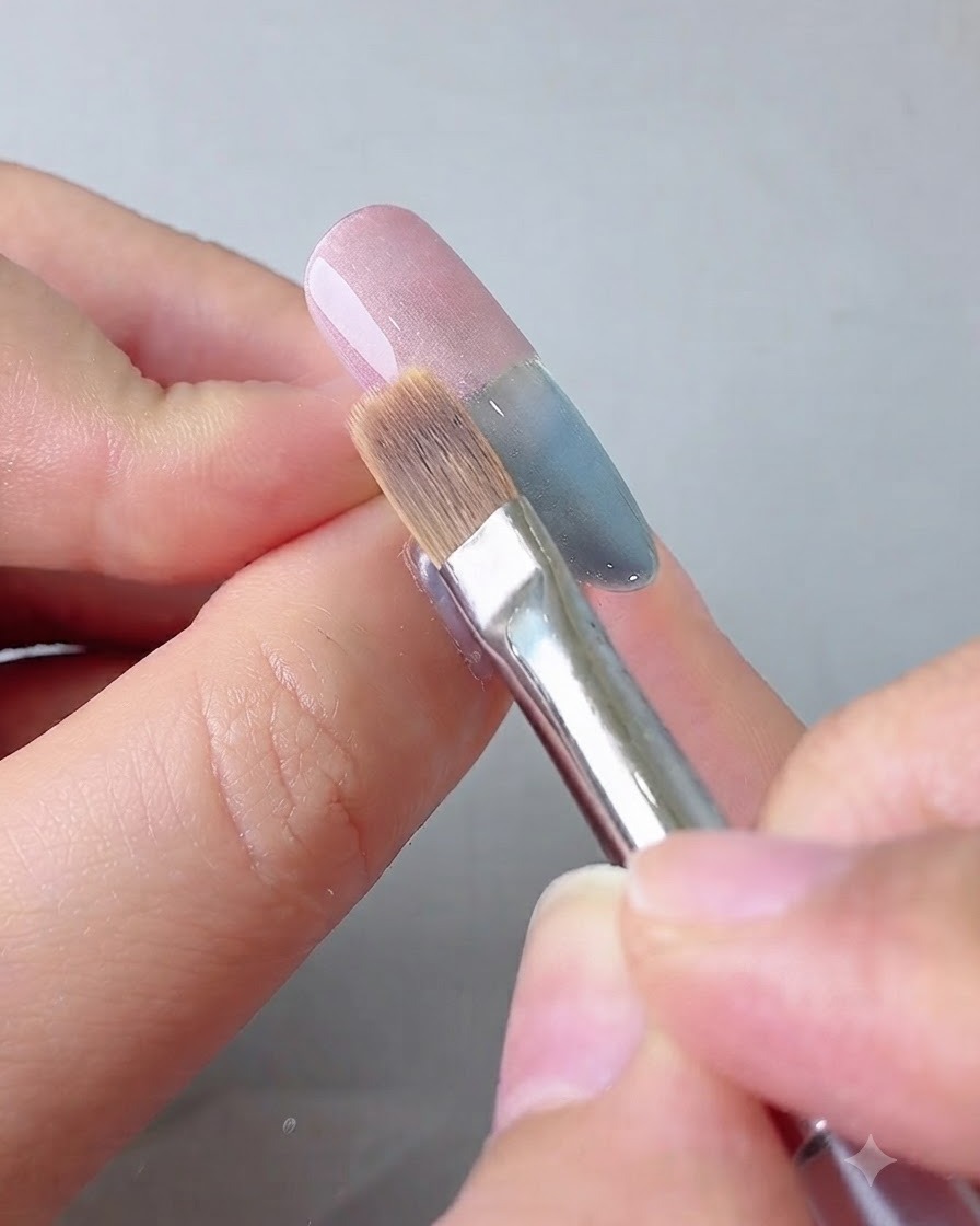 Un pinceau destompage étirant le gel rose vers le centre de longle.