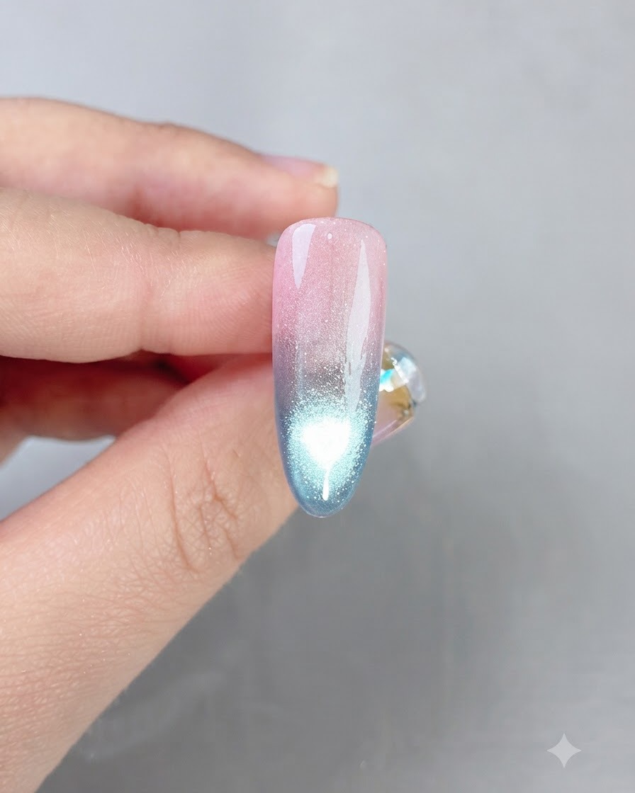 Un ongle fini en dégradé rose et bleu affichant une ligne de reflet cat eye brillante au centre.