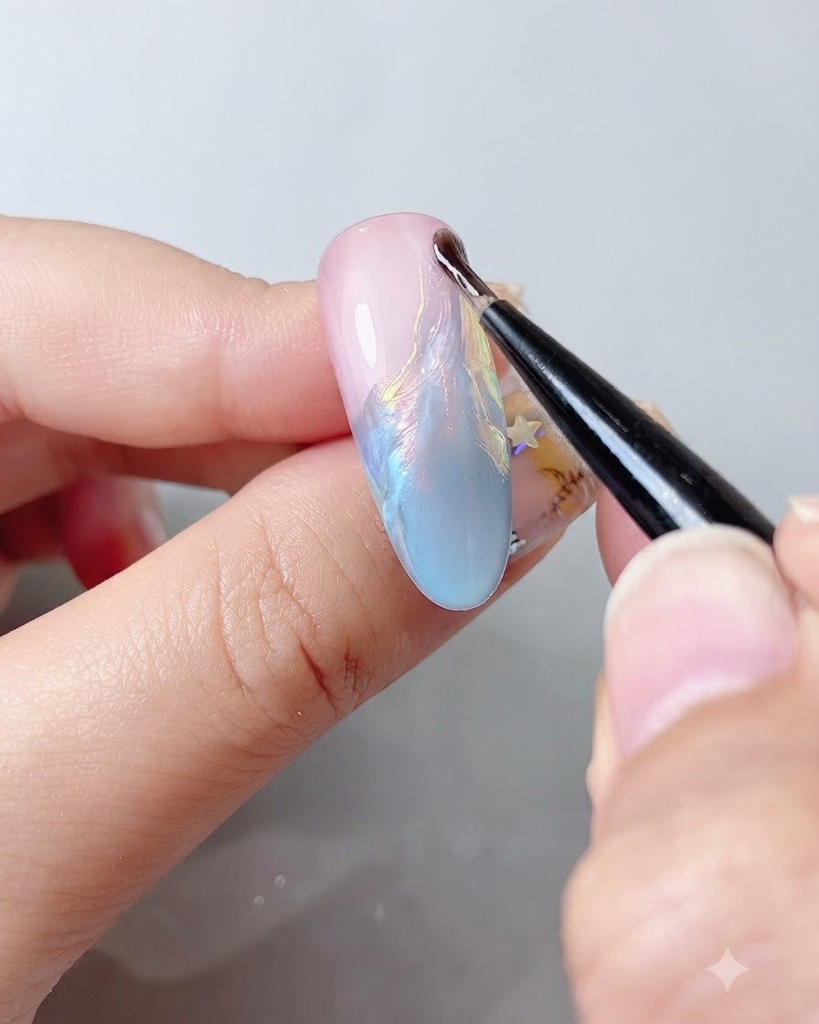 Un pinceau à ongle fin appliquant un top coat transparent sur une surface dongle chatoyante et multicolore.