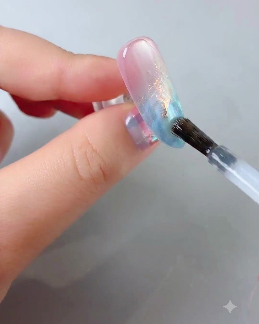 Un pinceau à ongle faisant glisser un top coat transparent et brillant sur la surface de longle décoré.