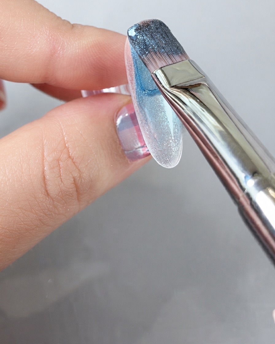 Un pinceau appliquant un vernis gel bleu riche sur toute la surface dun ongle.