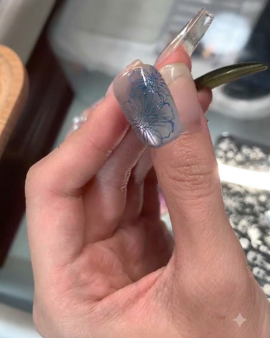 Un tampon en silicone transparent appliquant un délicat motif floral bleu sur le bout dun index.