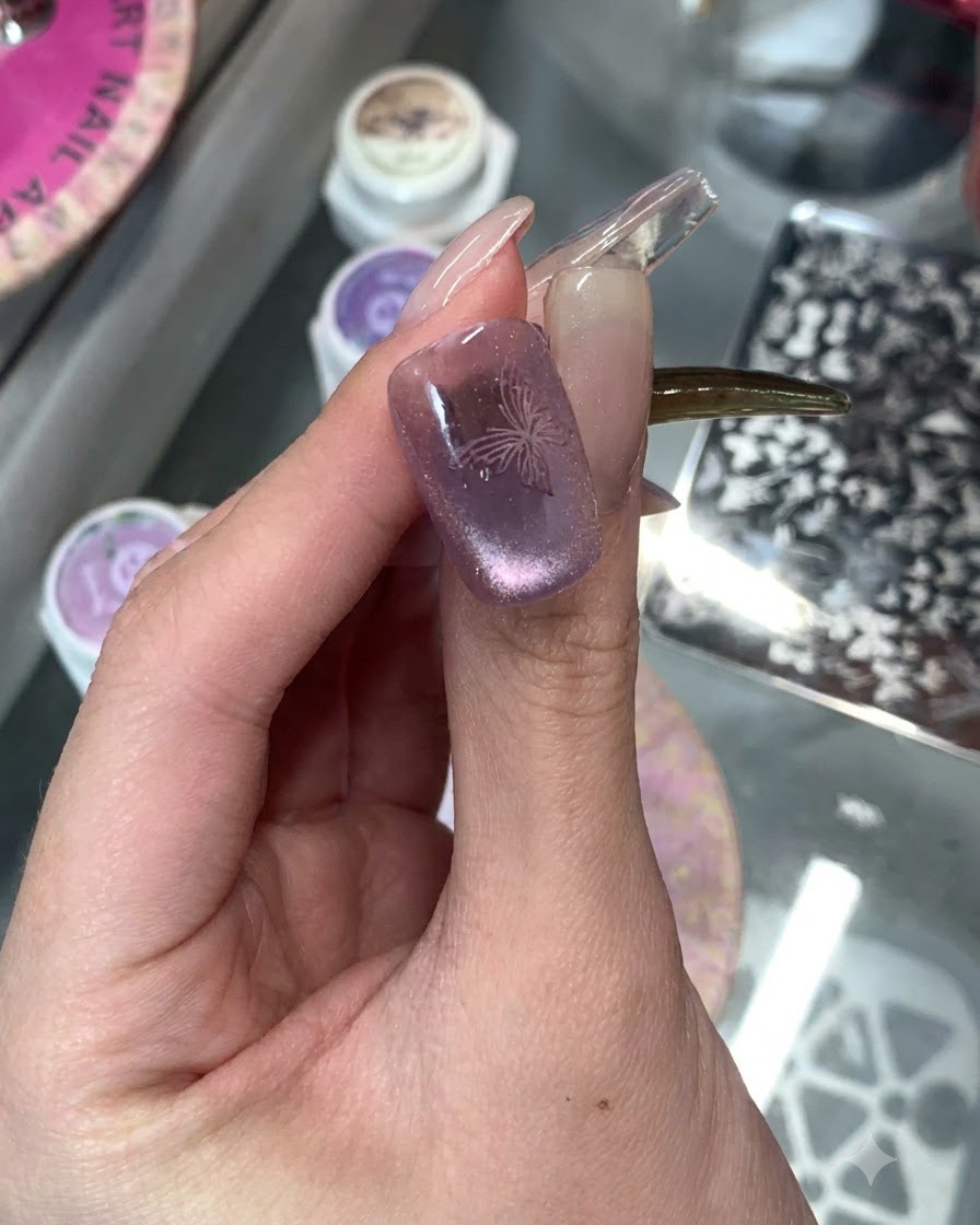 Gros plan dun ongle violet œil-de-chat avec un design de papillon délicat estampé sur le dessus.