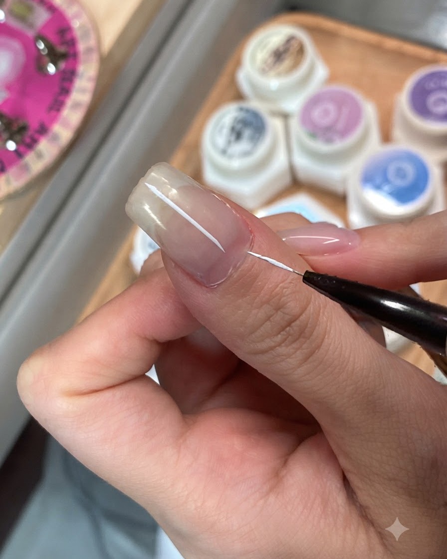Un pinceau de détail fin appliquant une couche de finition sur un seul ongle.
