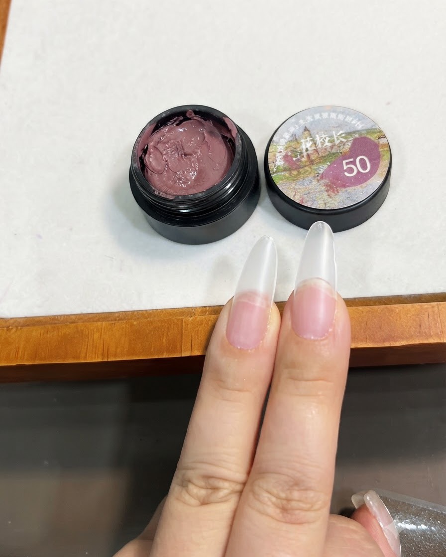 Un pinceau tenant une petite quantité de gel solide rose pâte de haricot près de lextrémité dune extension dongle transparente.