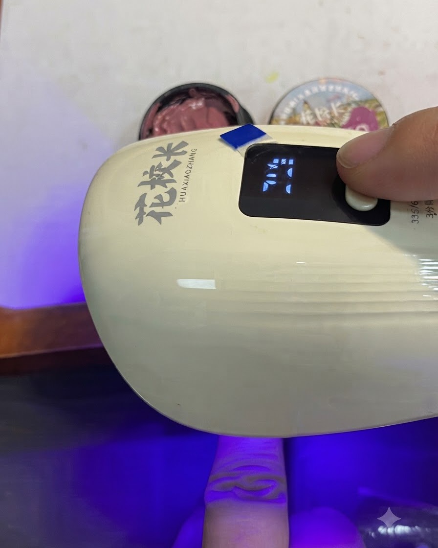 Un pinceau appliquant uniformément un gel œil-de-chat rose pâte de haricot doré scintillant sur toute la surface de longle.