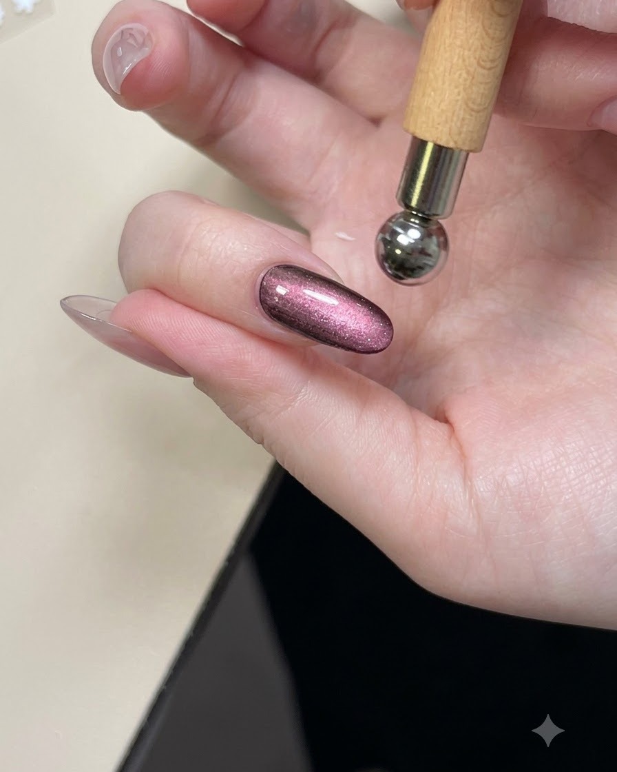 Un outil aimanté maintenu au-dessus dun ongle brillant en gel cat eye violet pour modeler le reflet.
