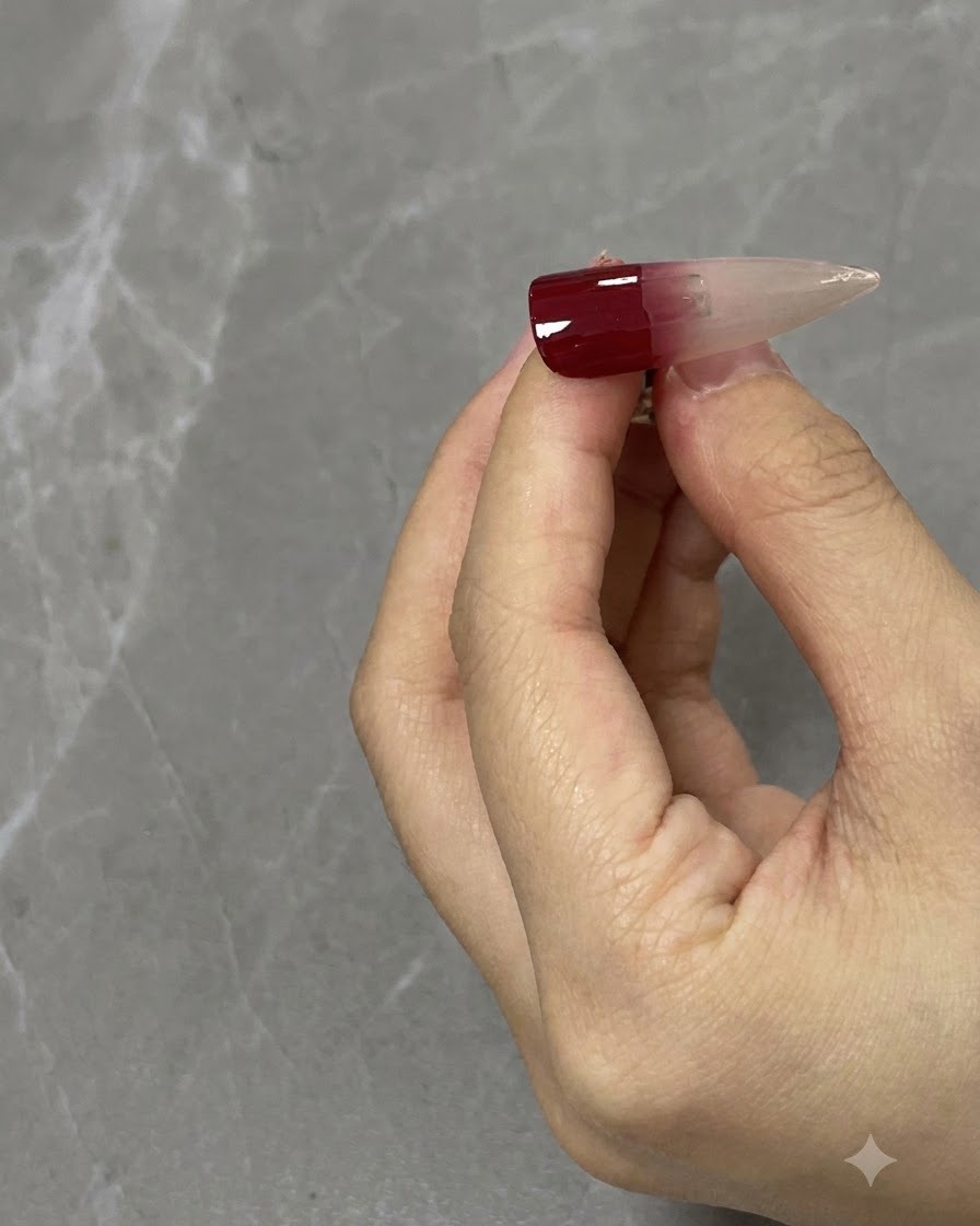 Un gros plan dun pinceau à ongles estompant un dégradé rouge vin vers le bas sur une capsule dongle neutre.