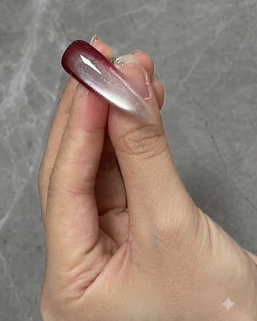 Un doigt avec un design dongle dégradé et cat-eye catalysé positionné sous une lampe de catalysation.
