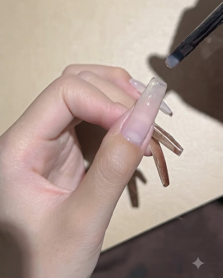 Un petit pinceau à gel appliquant une fine couche de gel de base transparent sur une plaque dongle rallongée.