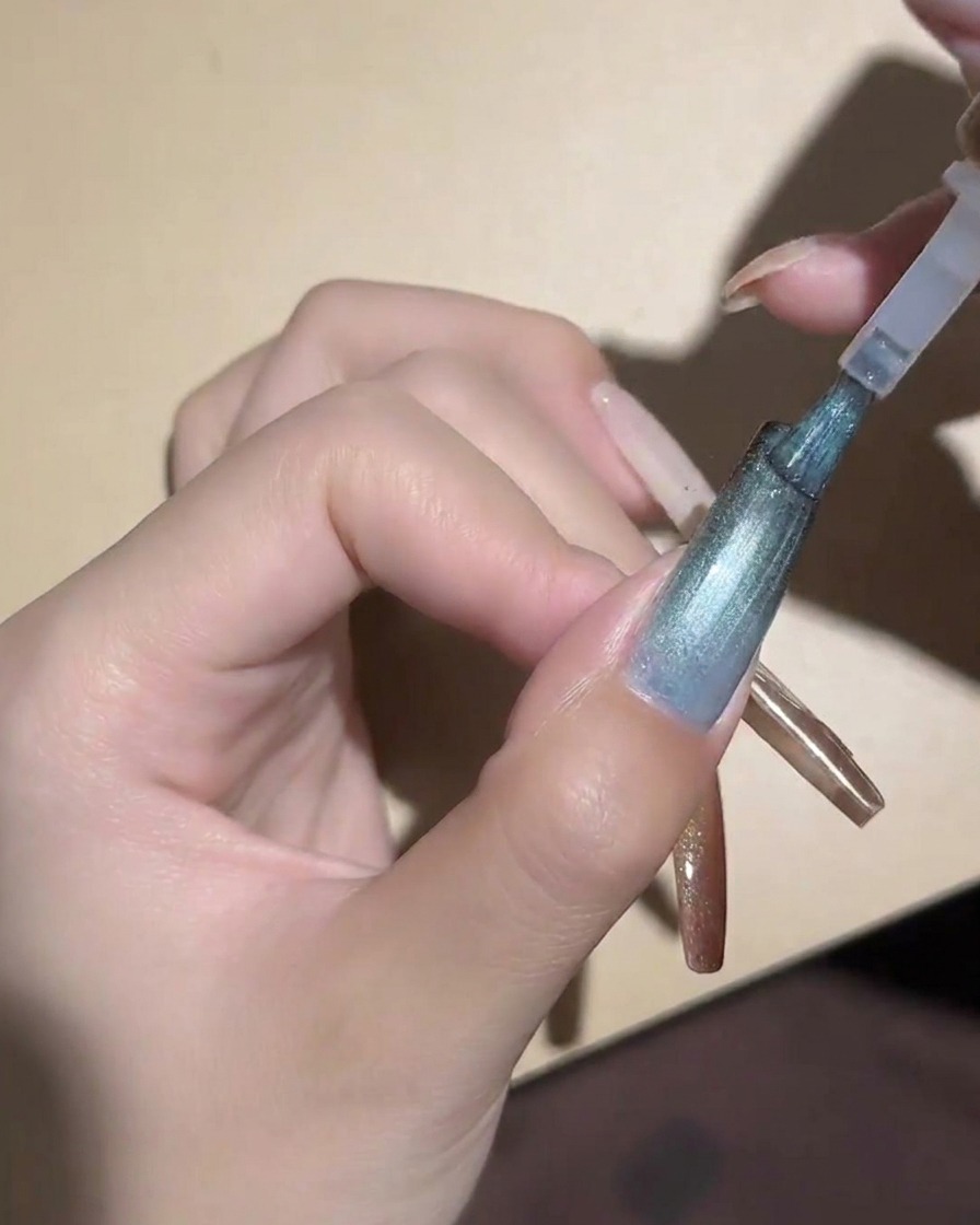 Un aimant cylindrique tenu près dun ongle œil de chat bleu pour magnétiser les particules.