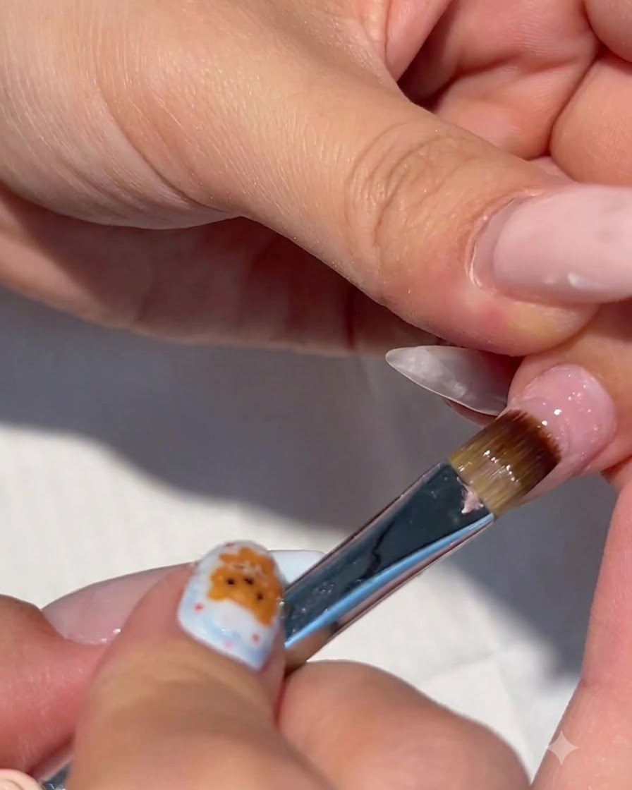 Un gros plan dun pinceau à ongles appliquant du gel de construction transparent sur un ongle préparé.