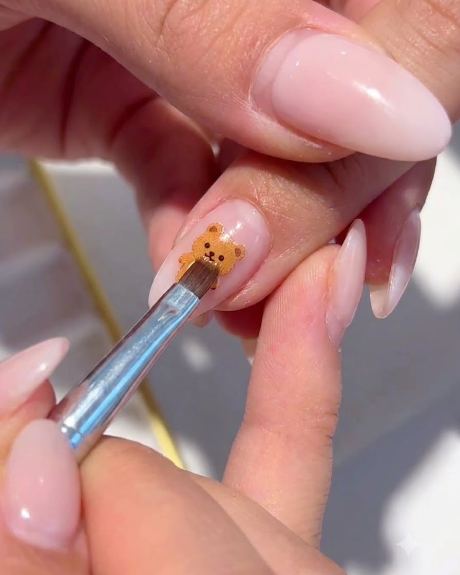 Un pinceau fin plaçant des paillettes irisées autour du nail art floral peint.