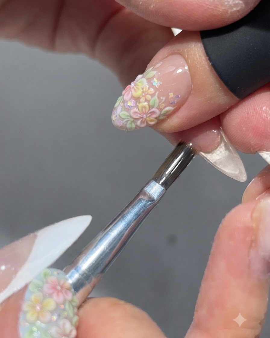 Un pinceau appliquant un top coat brillant sur un design dongle floral terminé.