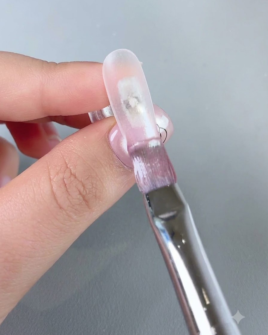 Un pinceau appliquant le gel aqueux transparent numéro 3 sur le bord avant dun ongle.