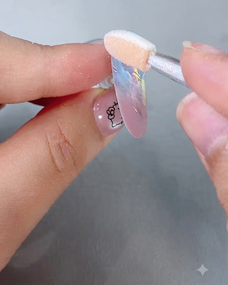Un applicateur éponge à fard à paupières polissant de la poudre miroir magique iridescente sur une capsule dongle de couleur pastel.