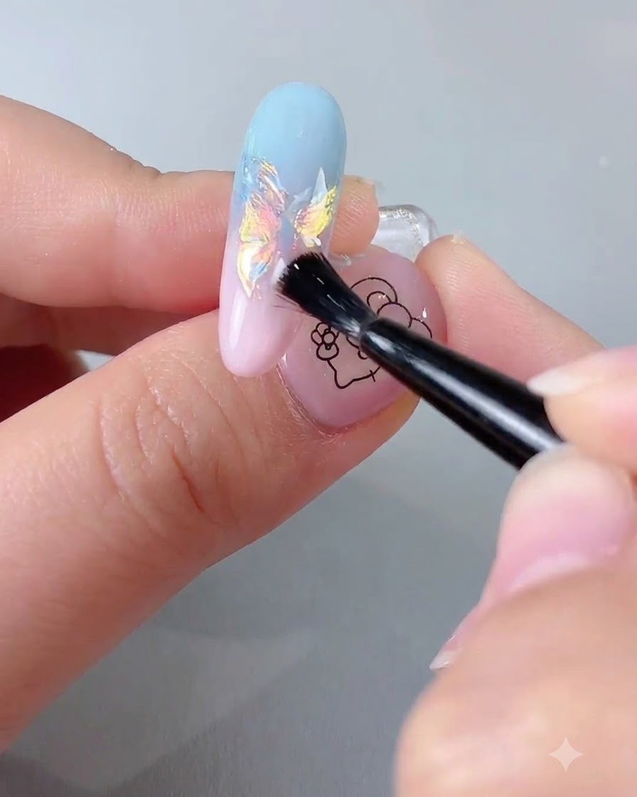 Un pinceau à ongles appliquant un top coat transparent scellant sur une extension dongle avec une finition chrome iridescente.