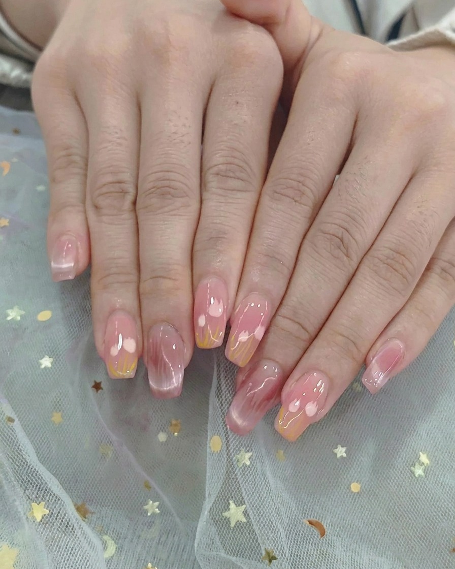 Un pinceau ombré estompant délicatement les vernis gel rose et jaune au milieu de longle.