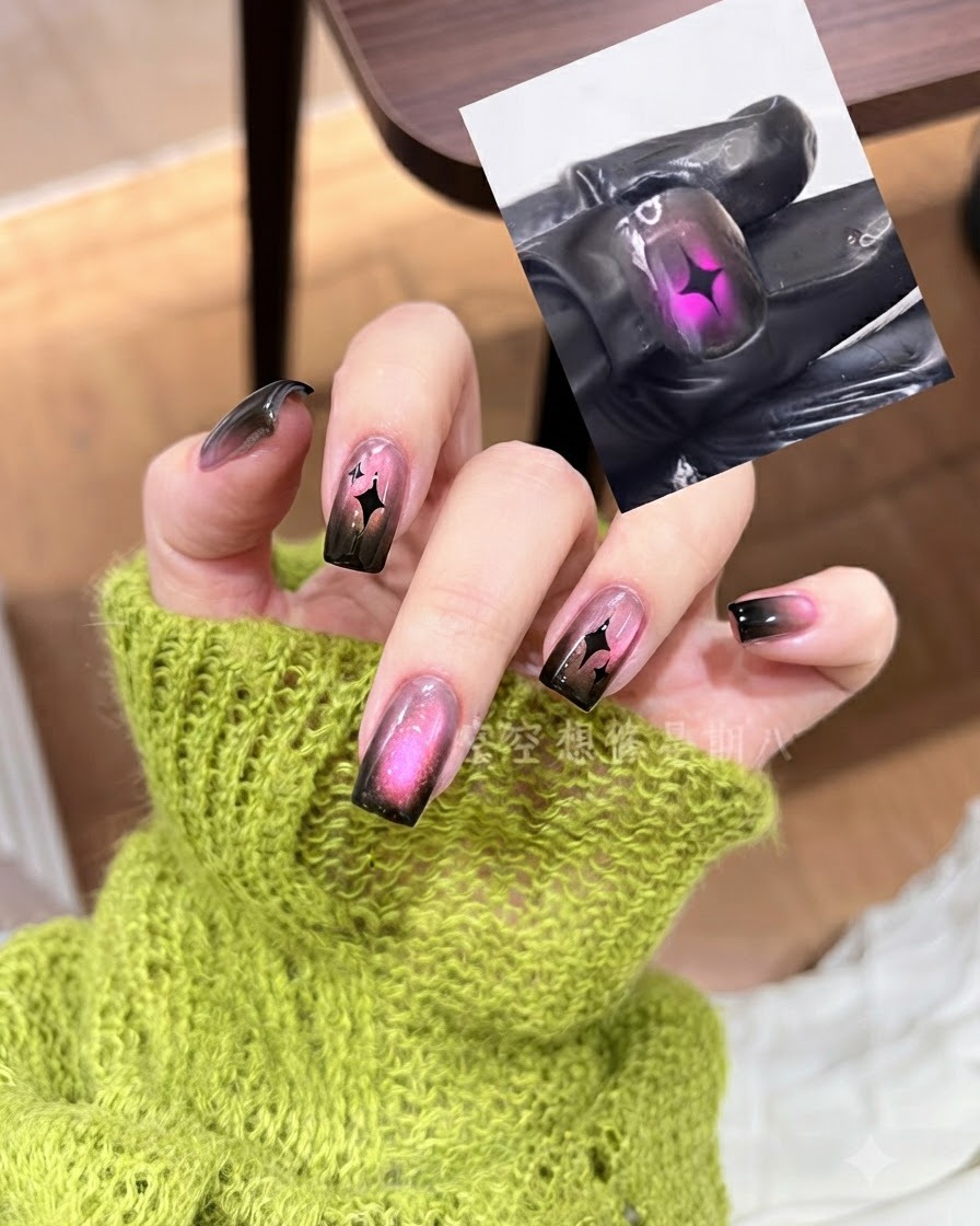 Un repousse-cuticules en métal pressant un sticker détoile noire sur un ongle dégradé rose et noir.