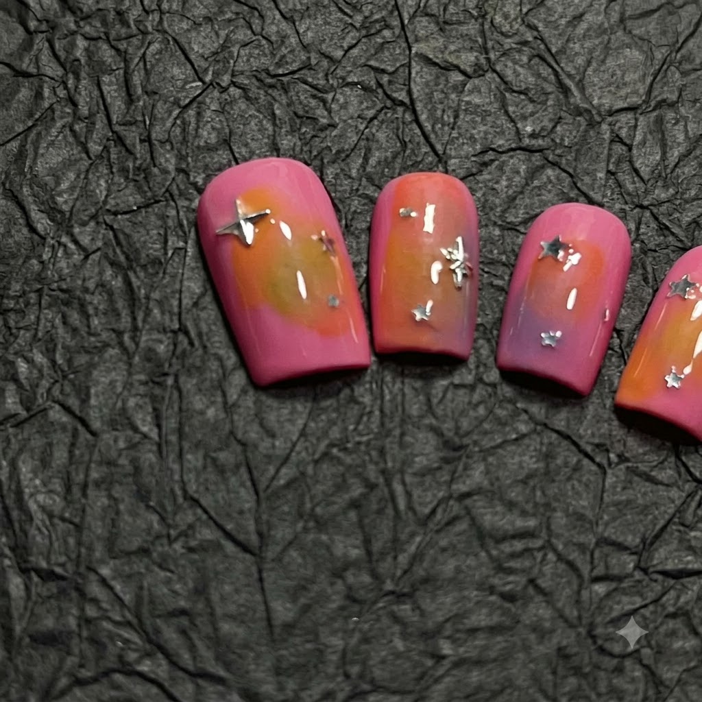 Une vue rapprochée dun ongle en dégradé rose et orange décoré de paillettes détoiles argentées éparpillées.