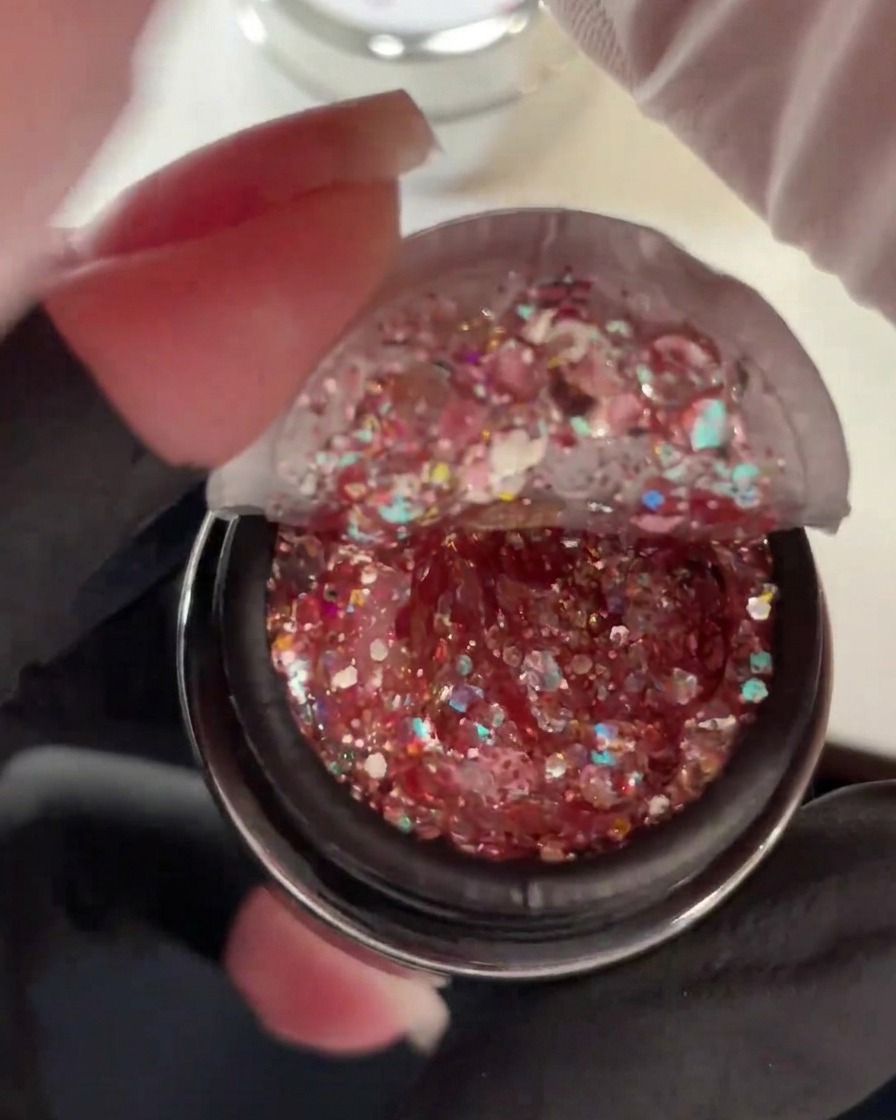 Pot ouvert de gel épais rempli de sequins de paillettes roses, holographiques et duochrome.
