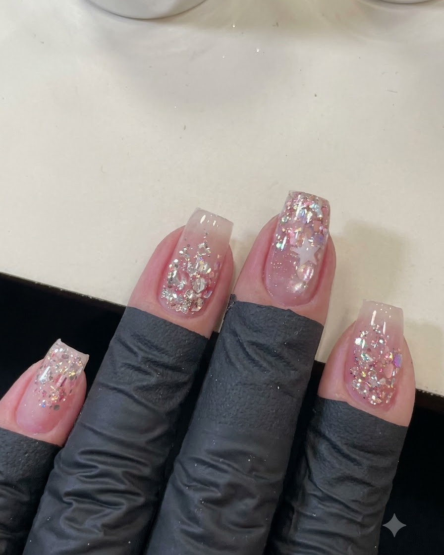 Vue aérienne de quatre ongles manucurés décorés de sequins roses scintillants et dun contour détoile.