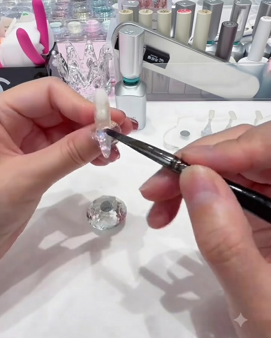 Un petit pinceau à ongles déposant des sequins circulaires colorés sur le gel de base humide près de la base de longle.