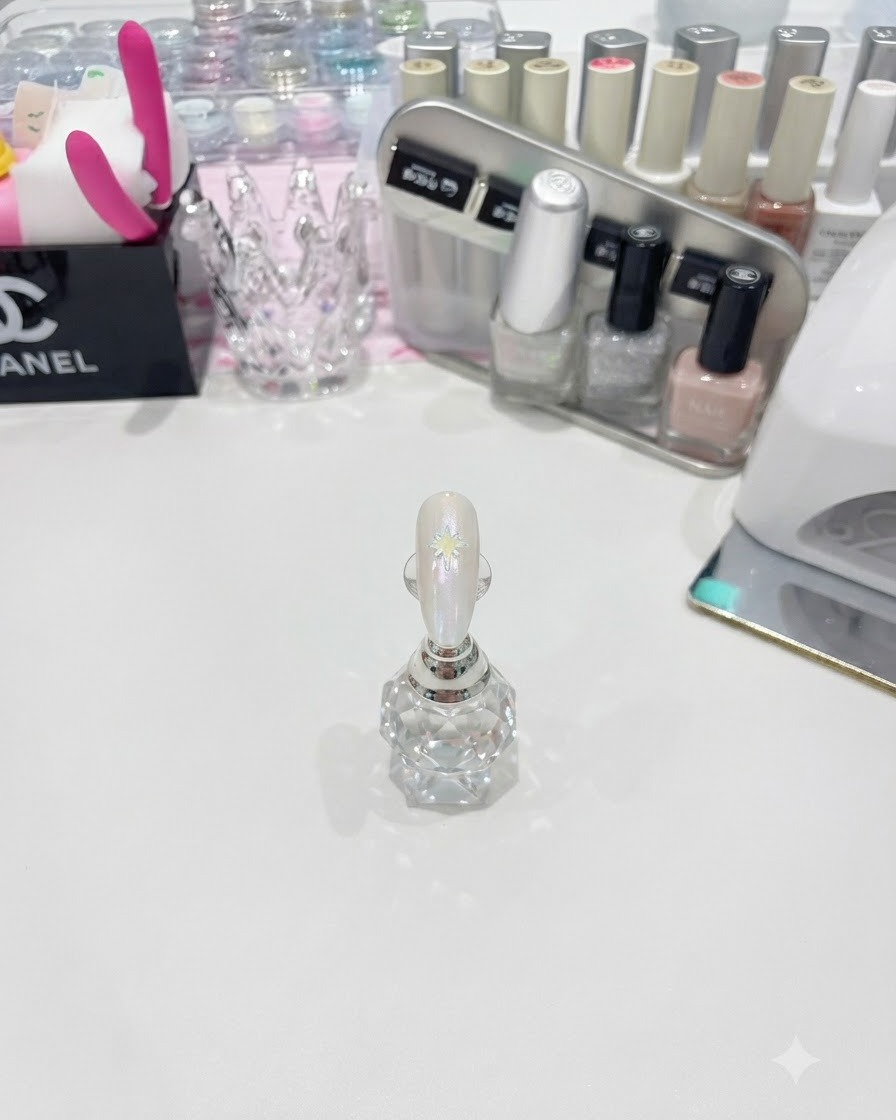 Un pinceau liner fin dessinant une grande étoile blanche à pointes multiples sur un ongle brillant.