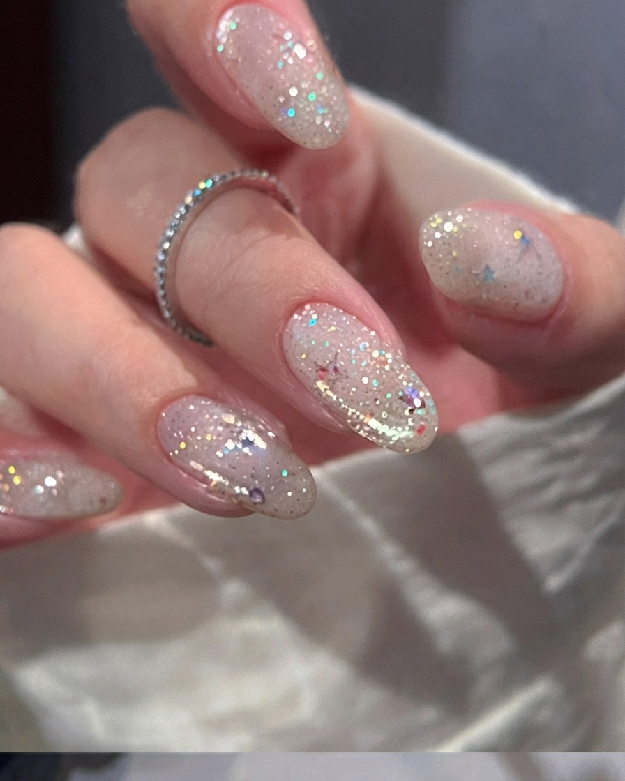 Un pinceau à ongles appliquant une couche lisse de vernis gel rose nude transparent sur un ongle naturel.