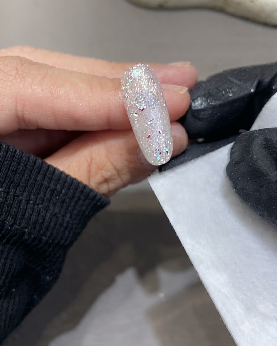 Une main gantée tenant une lingette non pelucheuse à côté dune surface dongle étincelante et catalysée.