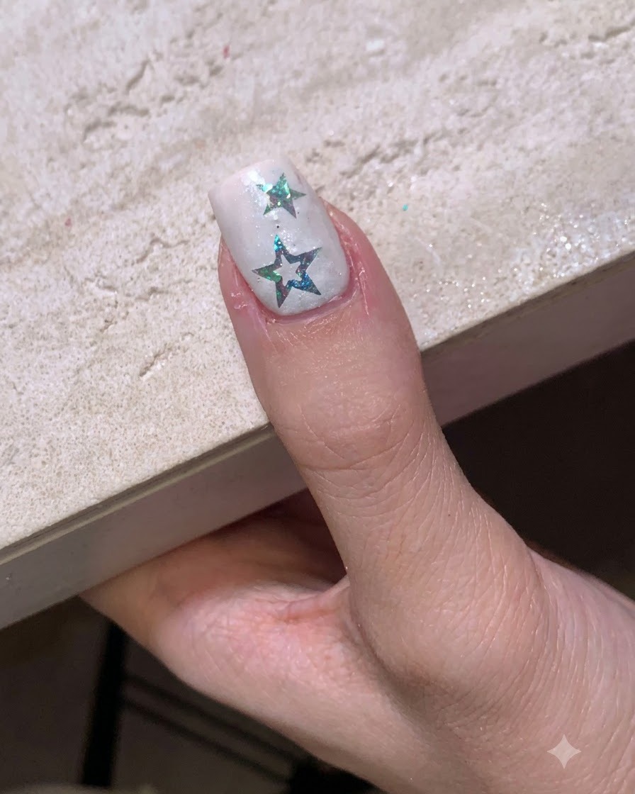 Un ongle avec des autocollants étoiles placé sous une petite lampe LED portable pour catalyser.