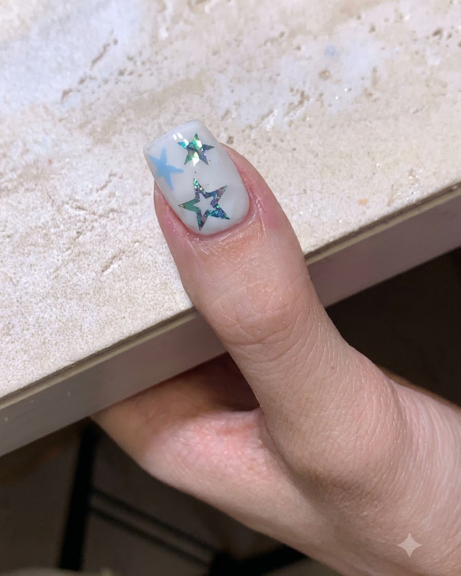 Une manucure sur le thème des étoiles terminée et catalysant sous une lampe à ongles.