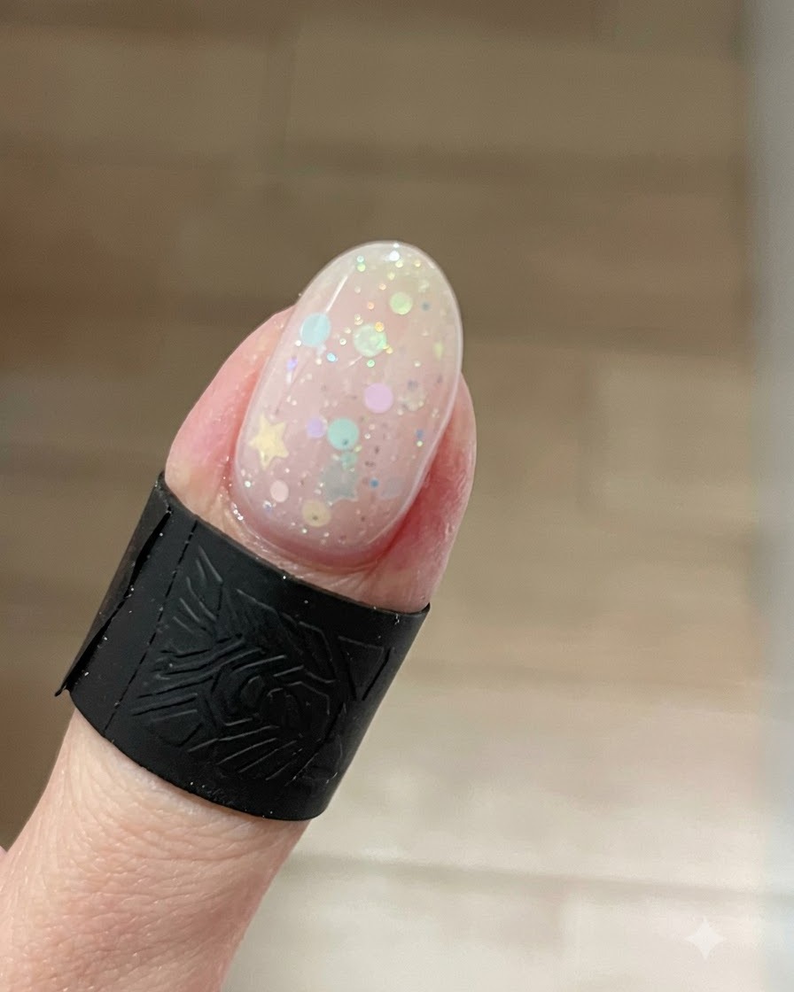 Gros plan sur un ongle présentant un effet gel cat-eye lumineux avec un scintillement intense concentré sur le bord libre au-dessus des étoiles.