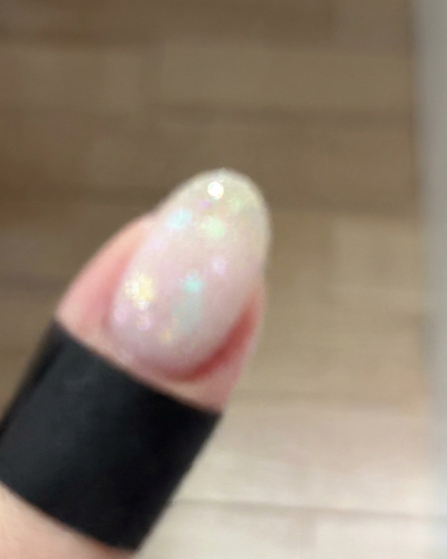 Une petite éponge à maquillage tapotant légèrement du gel rose poudré au centre dun ongle manucuré pour créer un dégradé effet blush doux.