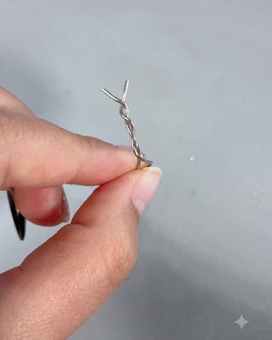 Une main tenant un bâtonnet magnétique avec une épingle à cheveux en métal torsadée fixée à son extrémité.