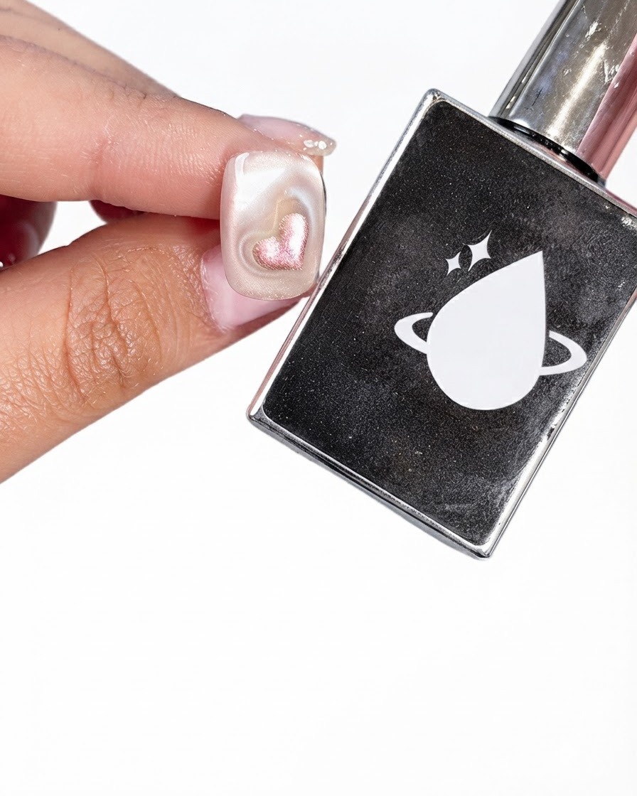Un ongle préparé tenu à côté dun flacon noir de top coat arborant un logo de planète blanche et une goutte.