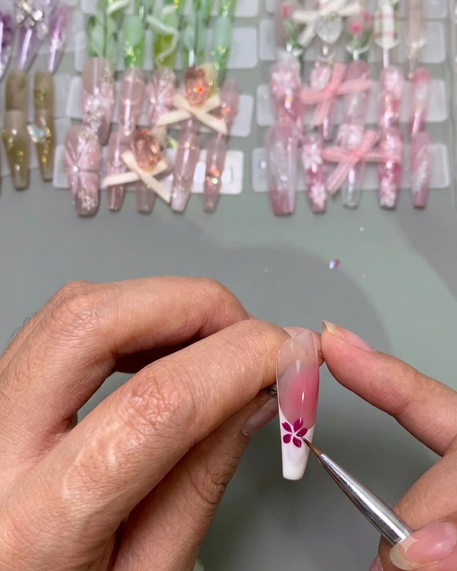 Un pinceau fin ajoutant des pétales bleus à côté dune fleur rose terminée sur un bout dongle.