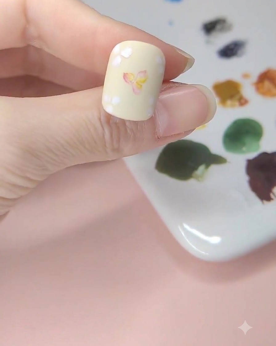 Un ongle jaune pâle montrant des lavis daquarelle jaune appliqués dans les espaces vides autour de lart floral.