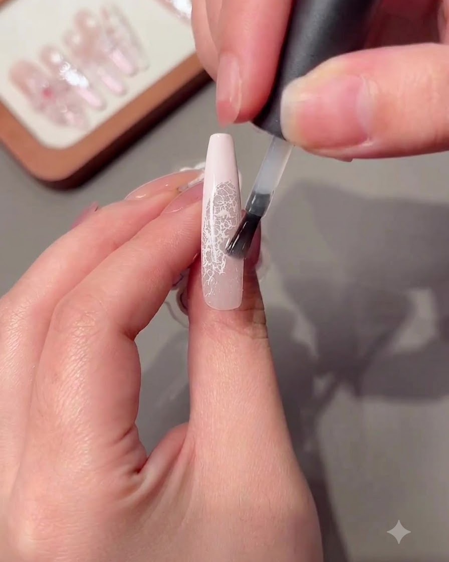 Un pinceau appliquant une couche de gel de construction transparent sur un ongle long.