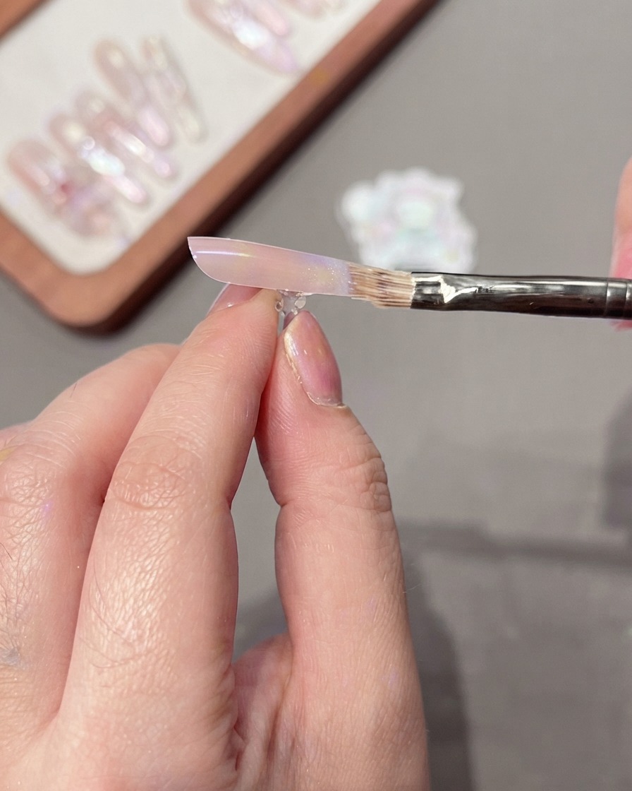 Un pinceau balayant doucement la surface de longle pour estomper un dégradé de couleur.