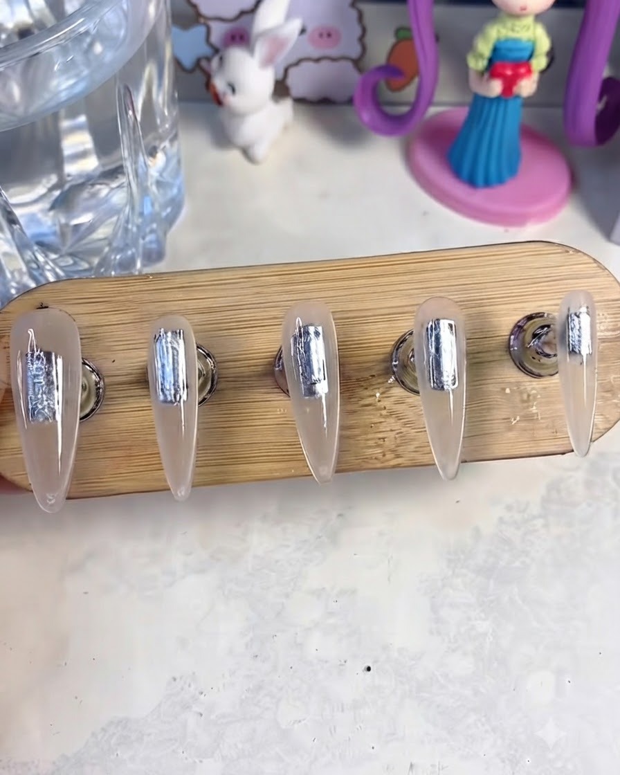 Un support à ongles avec cinq faux ongles placés à lintérieur dune lampe de catalysation UV/LED pour durcir la couche de gel de base.