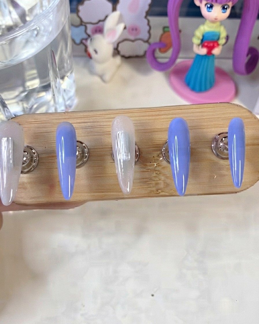 Un support à ongles montrant des ongles peints en bleu et en blanc laiteux en train de catalyser sous une lampe UV/LED.