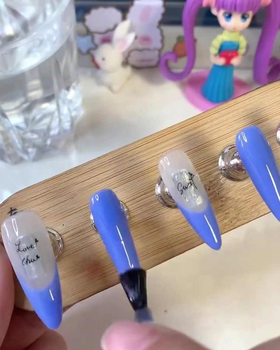 Un pinceau appliquant uniformément un top coat mat sur la surface des ongles peints sur un support en bois.