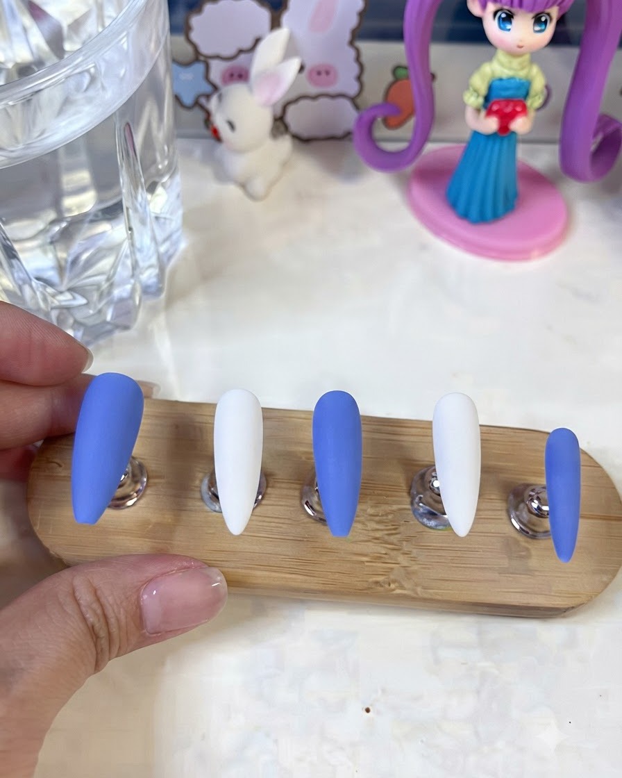 Ongles présentés sur un support montrant des détails de fleurs blanches en gypse et des lignes artistiques finies.