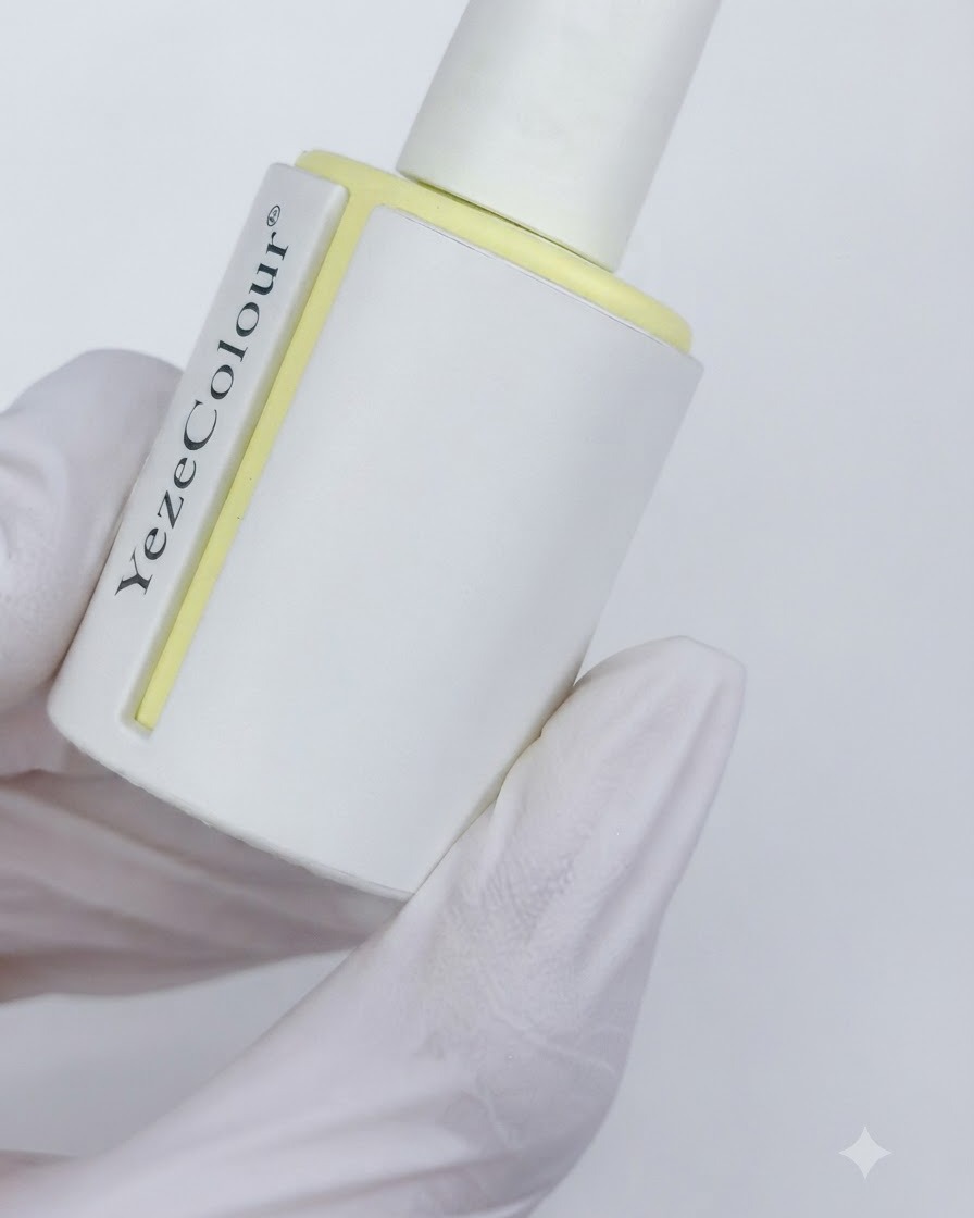 Un flacon de top coat velours mat étiqueté YezeColour tenu dans une main gantée.
