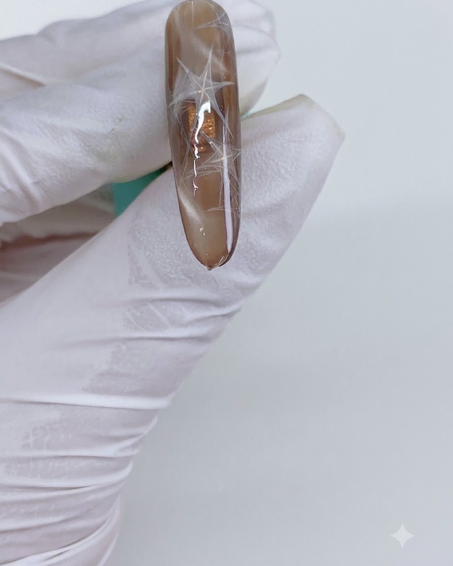 Un ongle manucuré avec des triangles cat eye placé sous une lumière de catalysation.