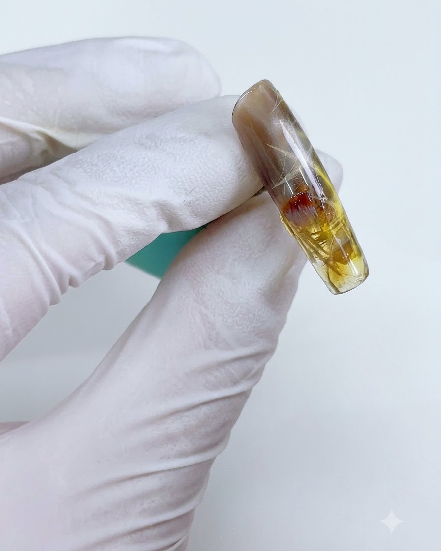 Un ongle avec un gel jaune-brun transparent appliqué localement sur le design stellaire.